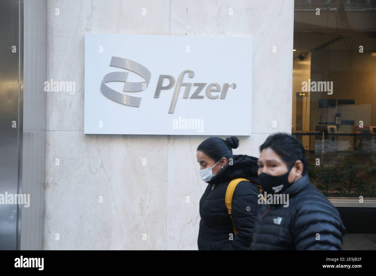 New York City, NY États-Unis les personnes portant des masques passent par le siège mondial de Pfizer sur la 42e rue à Manhattan Banque D'Images