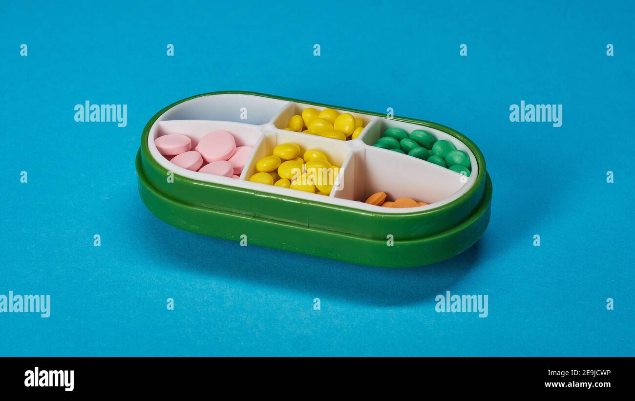Boîte de pilules verte sur fond bleu texturé. Photo de haute qualité Banque D'Images