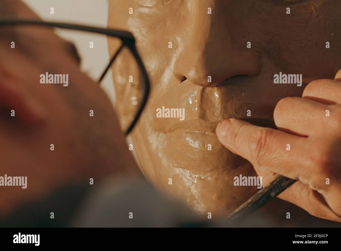 Un sculpteur forme les lèvres d'un buste en argile avec son doigt Banque D'Images