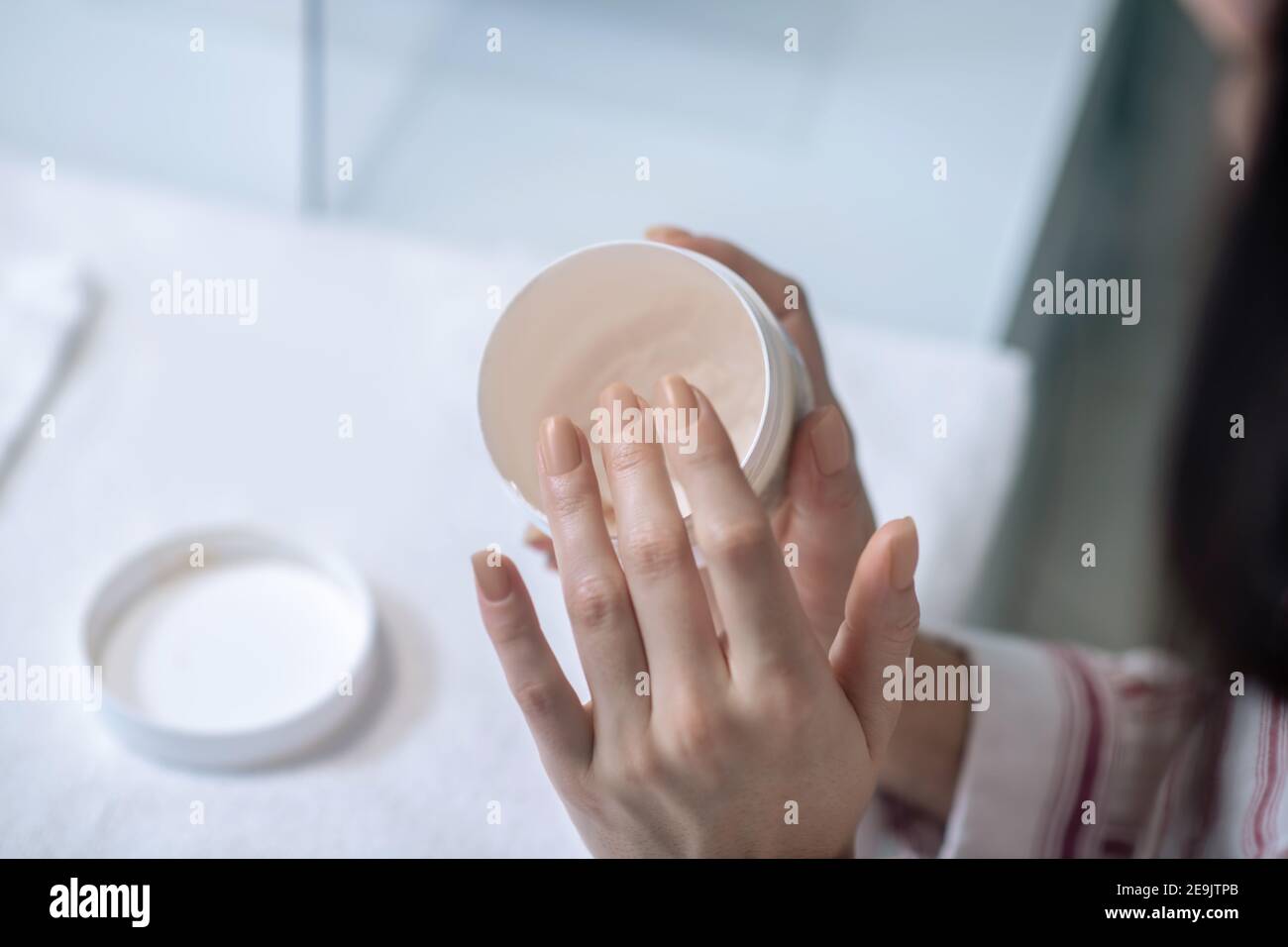 Gros plan des mains des femmes tenant un pot de main crème Banque D'Images