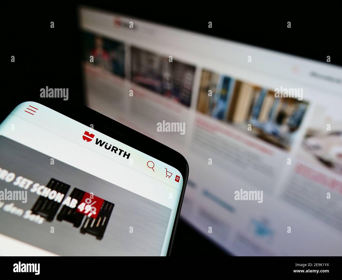 Personne tenant un téléphone portable avec site Web et logo de la société allemande de vente en gros Würth Group. Concentrez-vous sur la partie centrale supérieure de l'écran du téléphone. Banque D'Images