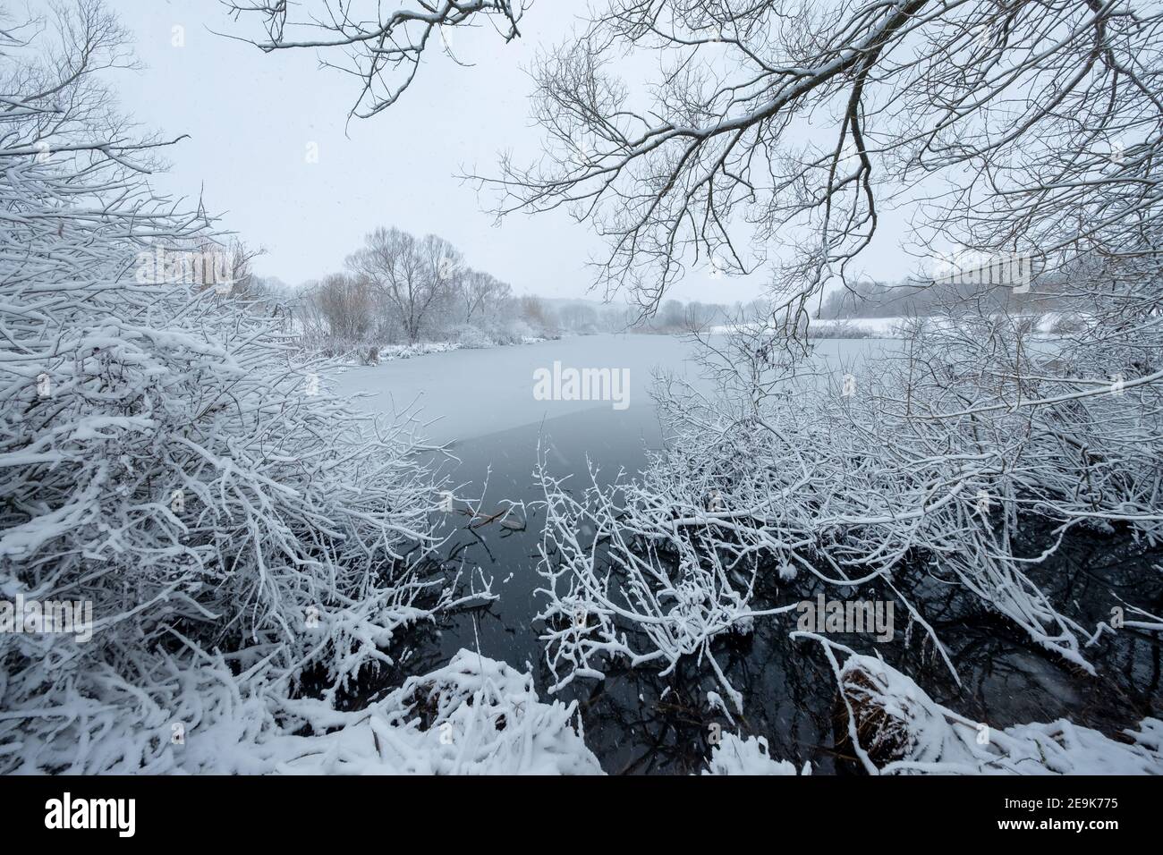 paysage d'hiver enneigé dans une ambiance calme et tranquille avec un lac entouré d'arbres Banque D'Images