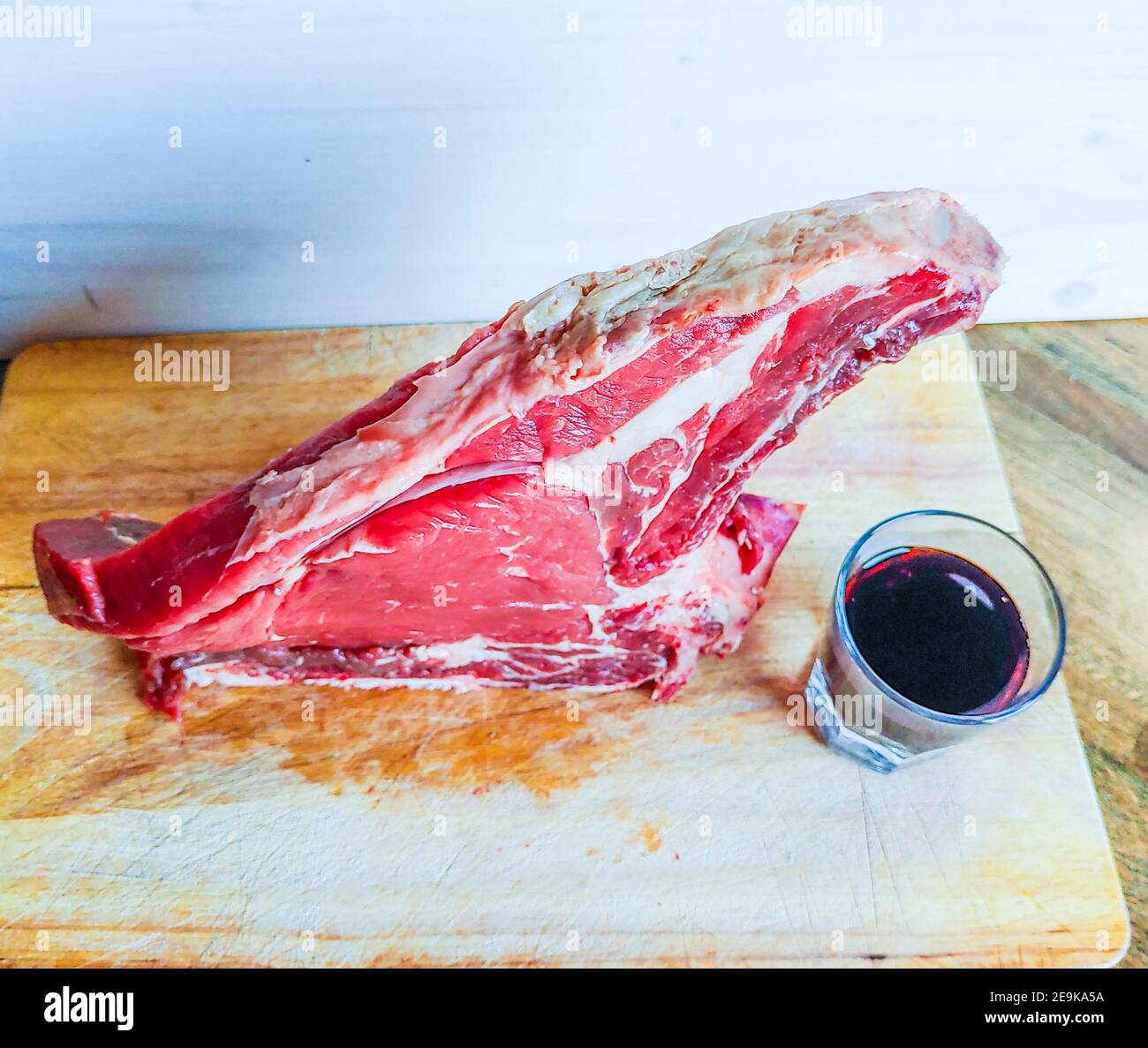 Steak de bœuf sur l'os, bien mûri, prêt pour votre barbecue et déjeuner, steak florentin, avec un verre de bon vin rouge authentique Banque D'Images Steak de bœuf sur l'os, bien mûri, prêt pour votre barbecue et déjeuner, steak florentin, avec un verre de bon vin rouge authentique Banque D'Images