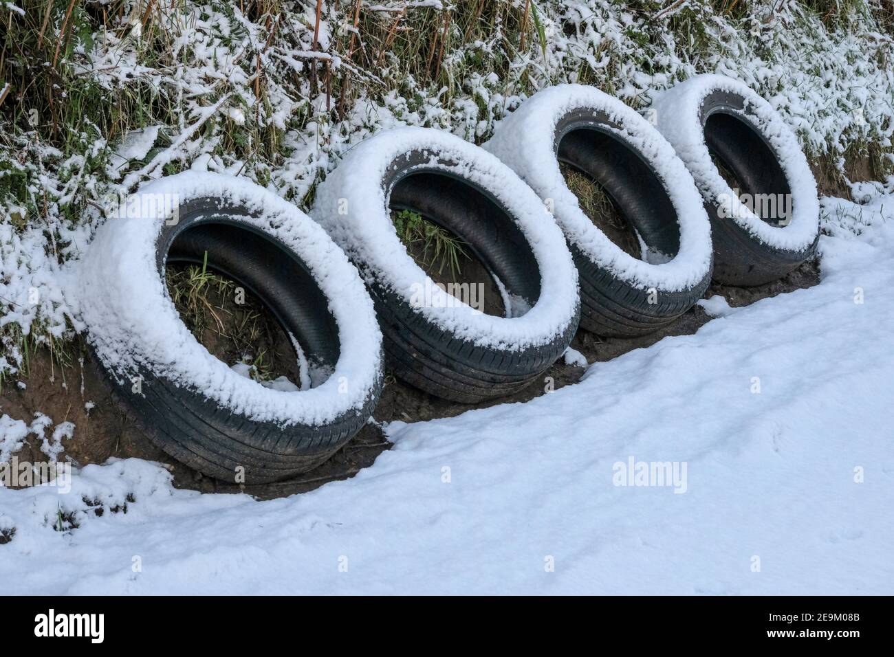 Quatre pneus déversés et abandonnés à un point de passage sur une étroite voie de campagne enneigée. Carmarthenshire. Pays de Galles. ROYAUME-UNI Banque D'Images