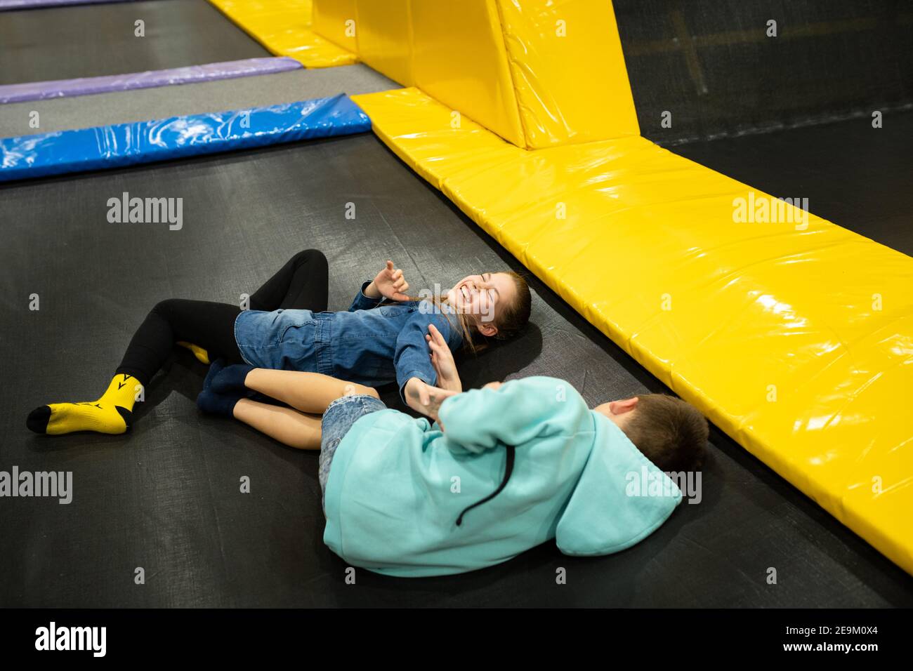 Mignon frère jumeau et soeur sauter et rebondir sur le trampoline intérieur ensemble quand passer du temps dans le centre de jeu d'enfants. Sports et divertissements Banque D'Images