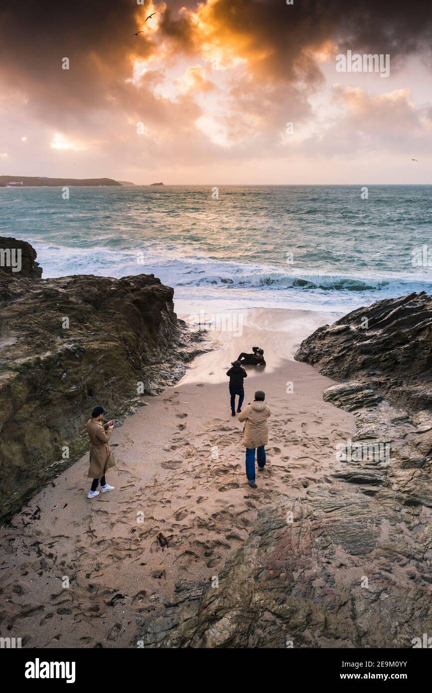 Coucher de soleil d'or comme quatre jeunes hommes posant pour des photos sur la plage dans une petite crique à Little Fistral à Newquay en Cornouailles. Banque D'Images