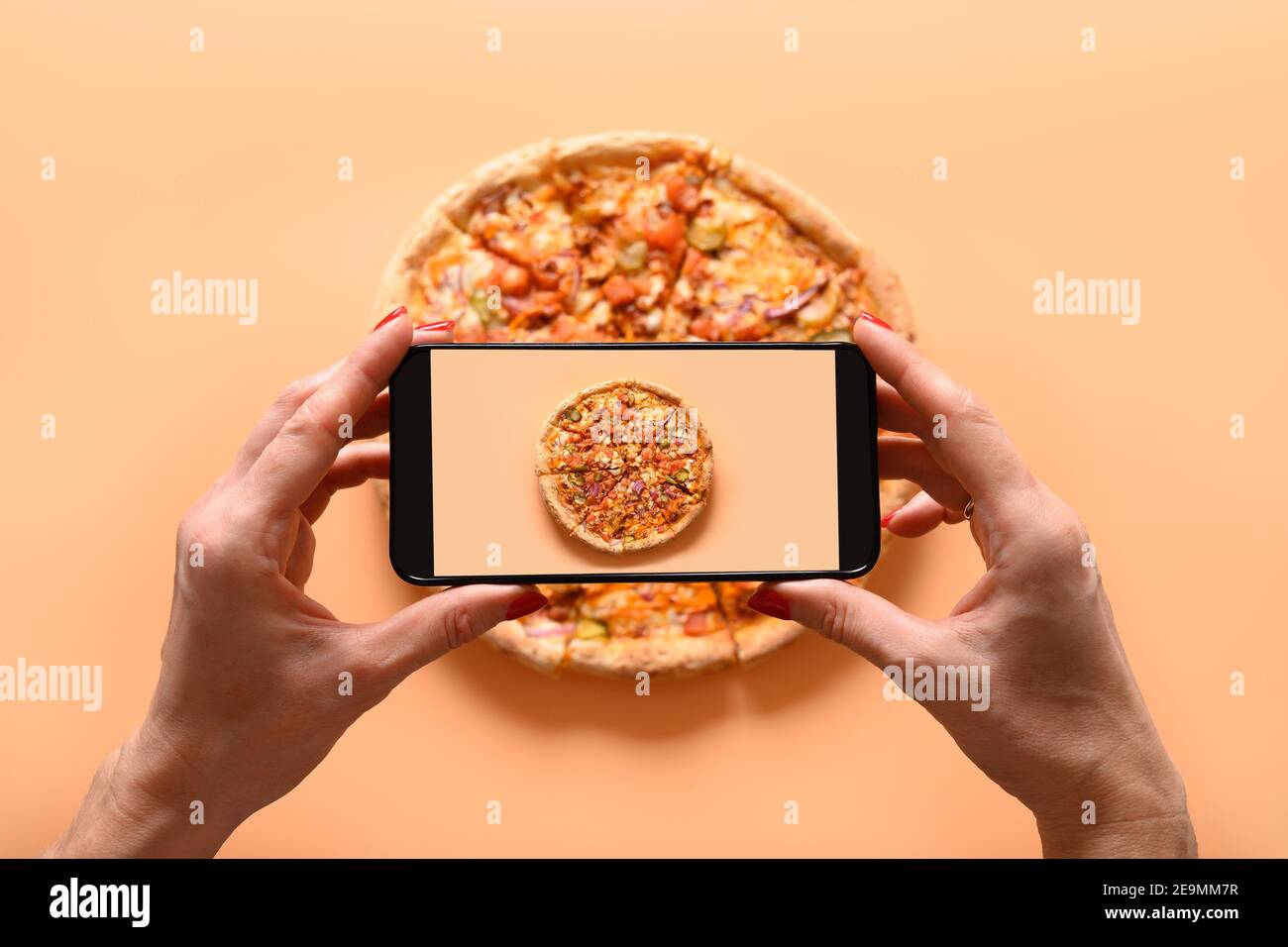 Femme mains prend la photographie de pizza végétalienne italienne avec tomate, mozzarella, sauce. Vue de dessus. Photo de smartphone pour les réseaux sociaux. Banque D'Images
