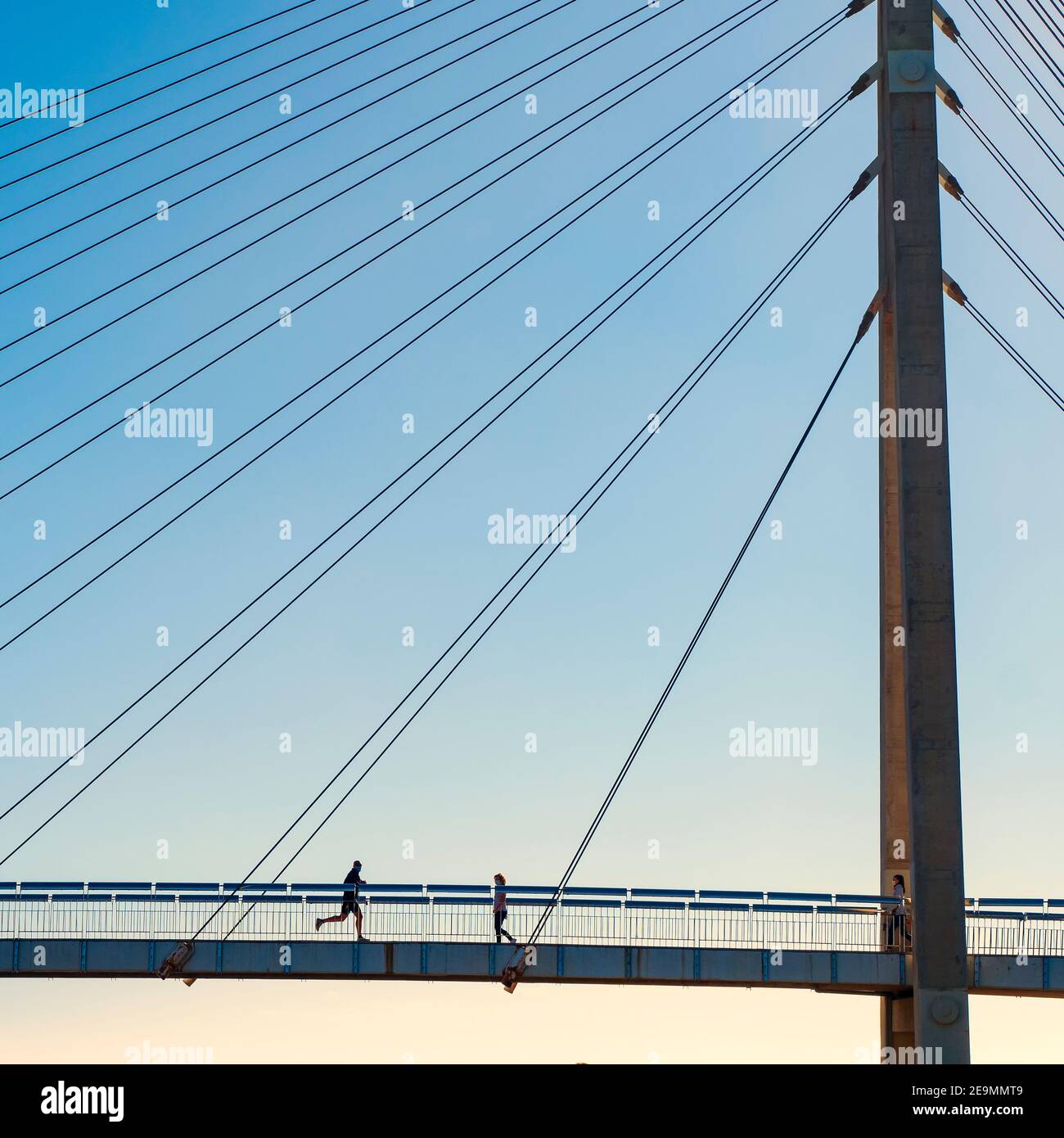 Un homme court dans une femme sur un pont suspendu en face de la mer lors d'une journée d'hiver ensoleillée à Fuengirola. Banque D'Images