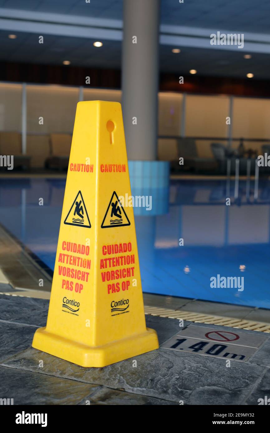 Signes de mise en garde sur les sols glissants et humides en plusieurs langues. Accroître la sécurité et la prudence au bord d'une piscine dans la station balnéaire. Plage et piscine en vacances Banque D'Images