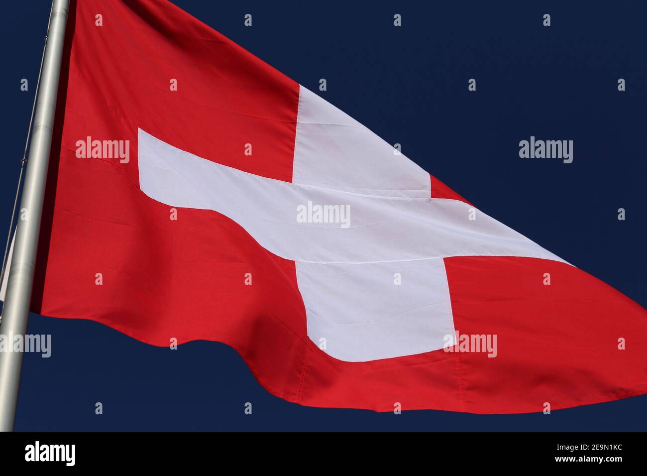 Le drapeau de la Suisse pendant une journée venteuse. Gros plan du drapeau rouge et blanc avec le ciel bleu en arrière-plan. Symbole de l'indépendance et de la nationalité. Banque D'Images