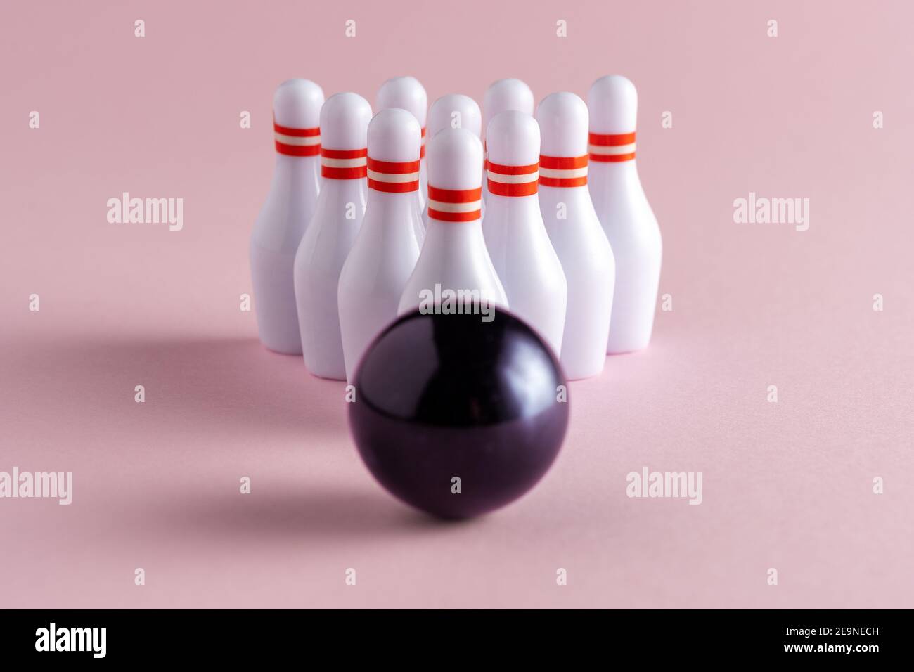 Boule de bowling et quilles blanches sur fond rose pastel. Concept créatif minimal. Banque D'Images