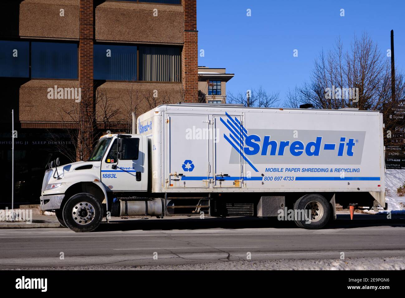 Un camion Shred IT stationné devant un immeuble de bureaux là où le conducteur saisit les papiers à déchiqueter Banque D'Images