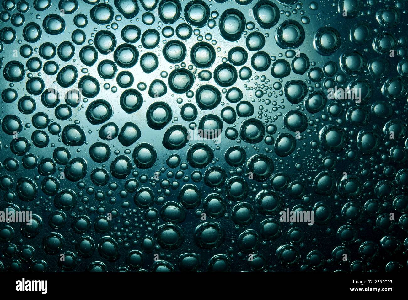 Bulles sur un fond intéressant, disposées de manière chaotique dans l'eau sur la surface en verre Banque D'Images