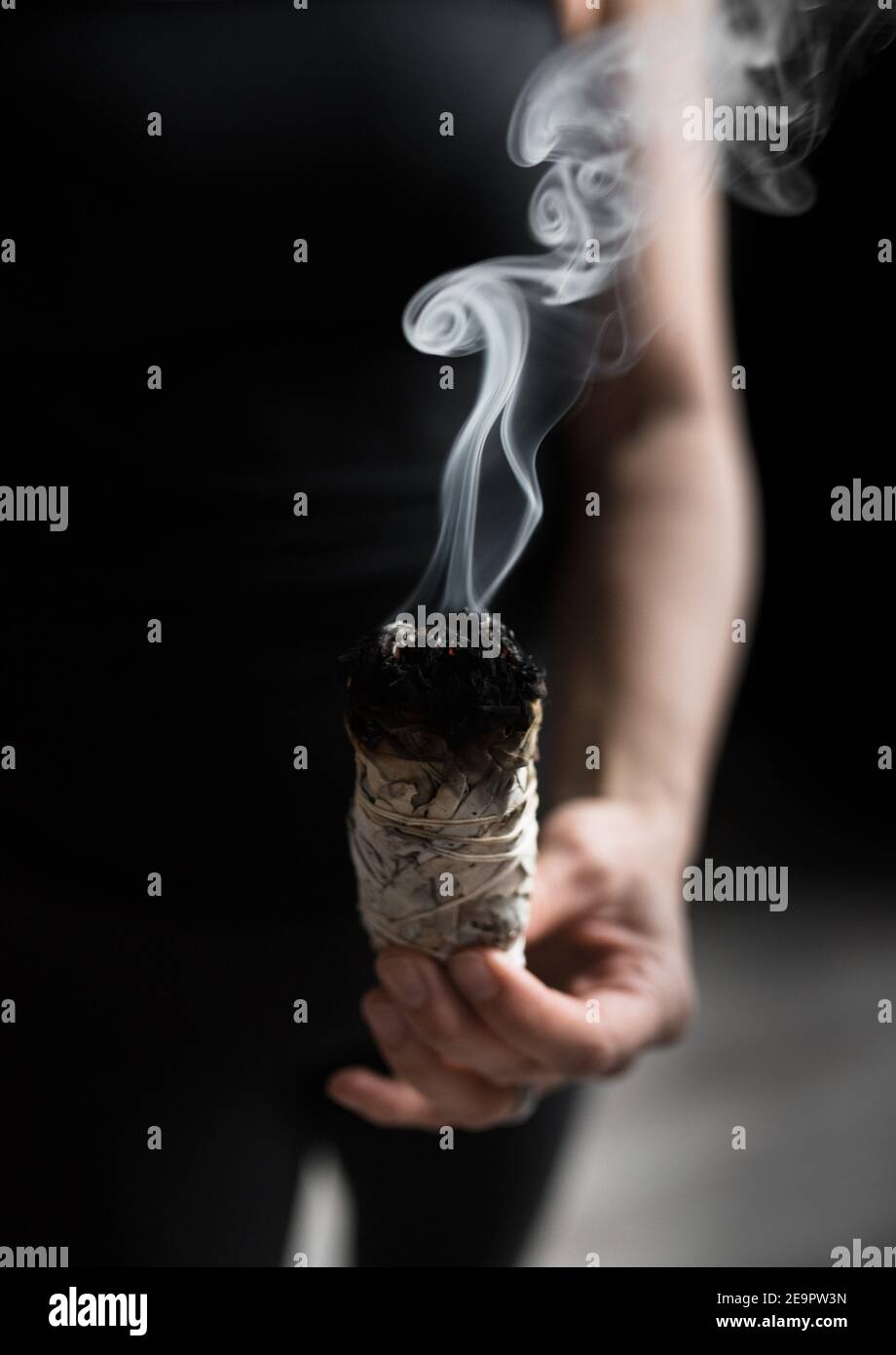 Femme main tenant le paquet d'herbe de sauge séchée bâton de taches Banque D'Images