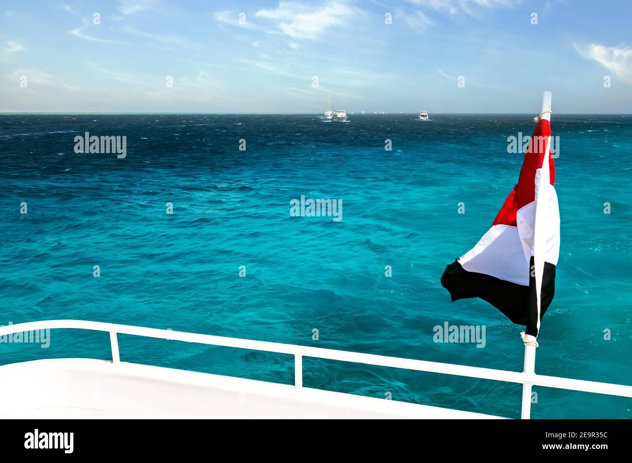 Drapeau national de l'Égypte agitant sur le vent de fond bleu ciel. Yachts blancs touristes dans l'eau d'azur Mer Rouge, République arabe d'Egypte. Banque D'Images
