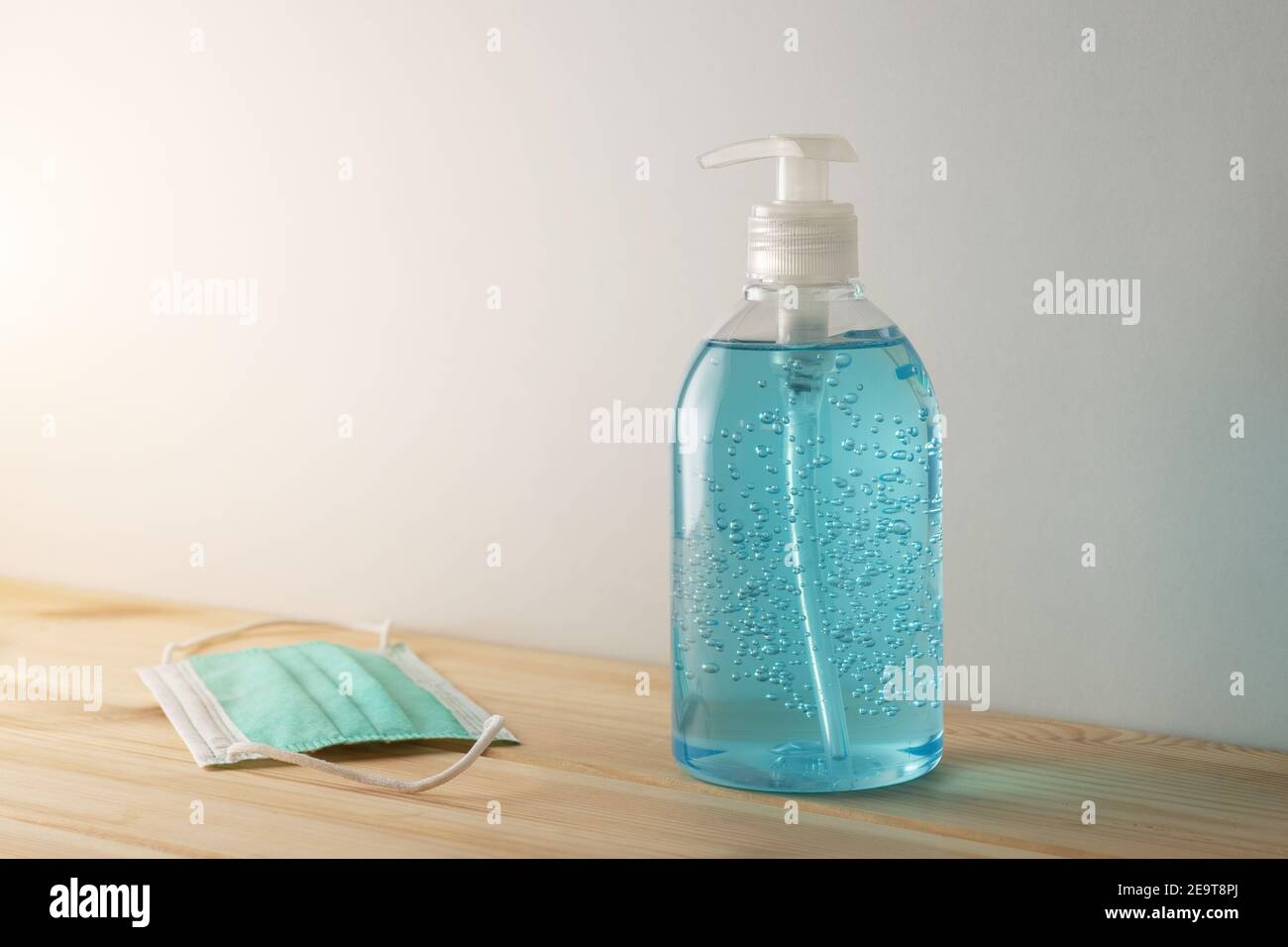 Désinfectant pour les mains dans une bouteille avec masque médical sur une table en bois. Concept de prévention des coronavirus. Banque D'Images