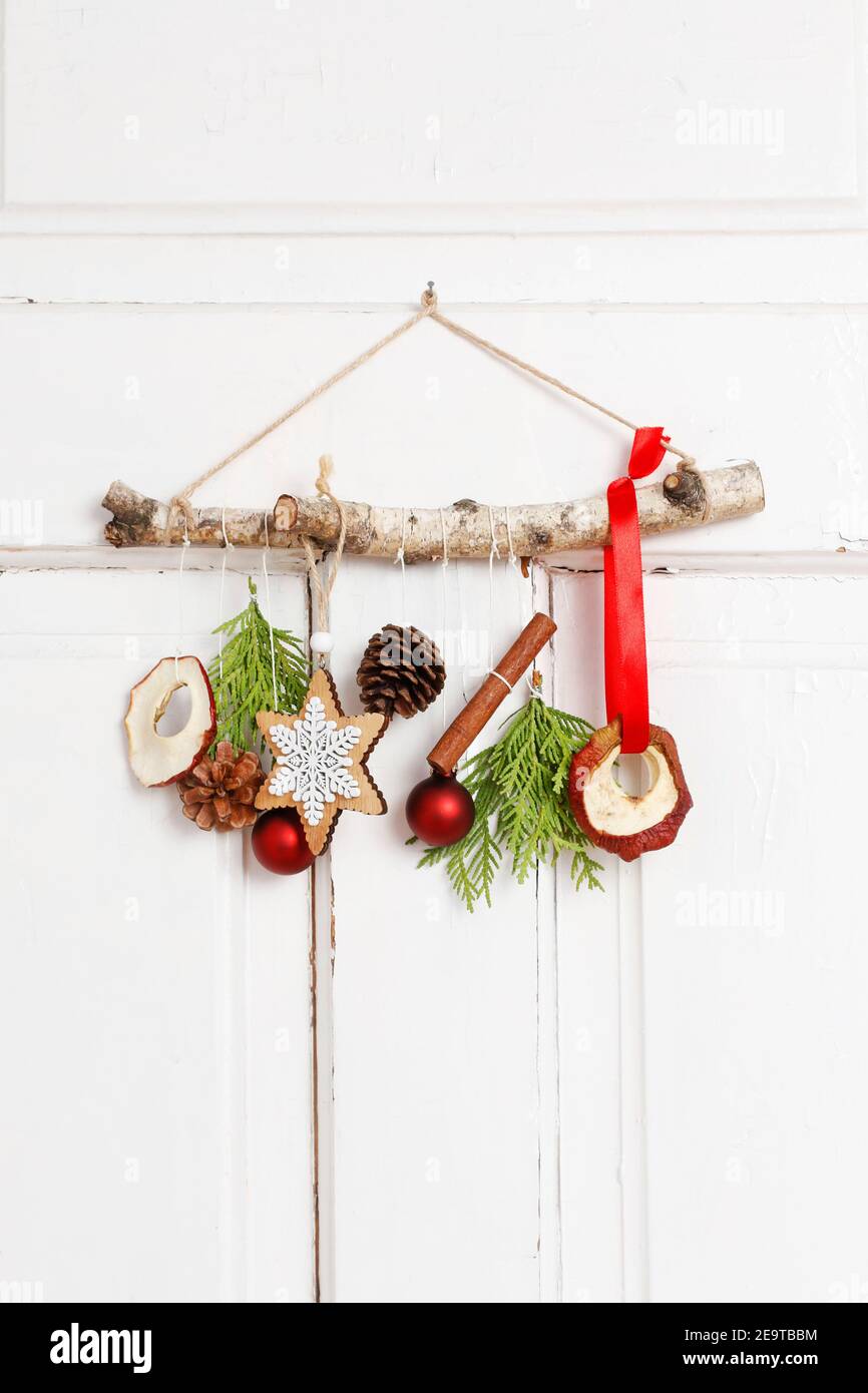 Fleuriste au travail: Femme montre comment faire une décoration de Noël naturelle, en utilisant un bâton de bouleau, des brindilles de thuya, des cônes et des pommes séchées. Étape par étape, tuteur Banque D'Images
