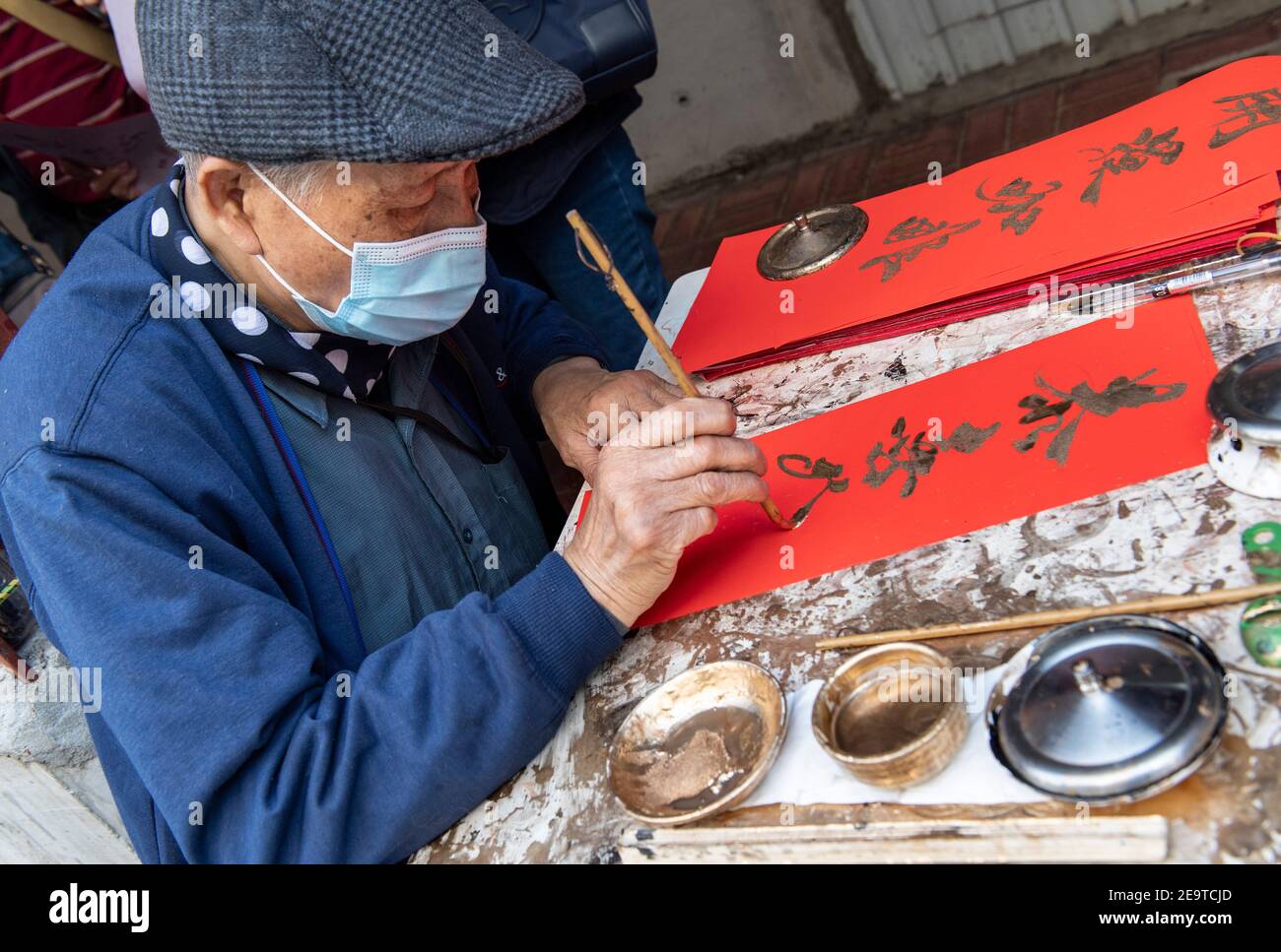 HONG KONG, HONG KONG SAR, CHINE : 6 FÉVRIER 2021. Une calligraphie sifu (maître) travaille sur le côté d'une route très fréquentée à Causeway Bay Hong Kong, produisant des couplets cantonais peints à la main prêts pour le nouvel an chinois. Il peint les personnages de Gong hei FAT choy (qui vous souhaite la prospérité!), une expression populaire du nouvel an. Ces couplets lunaires rouges du nouvel an ou cheun lyun, sont utilisés comme décoration et ont beaucoup de différents messages favorables écrits sur eux. CNY commencera le vendredi 12 février 2021 avec les vacances annonçant l'année du zodiaque de l'Ox. Alamy Live News/Jayne Russell Banque D'Images