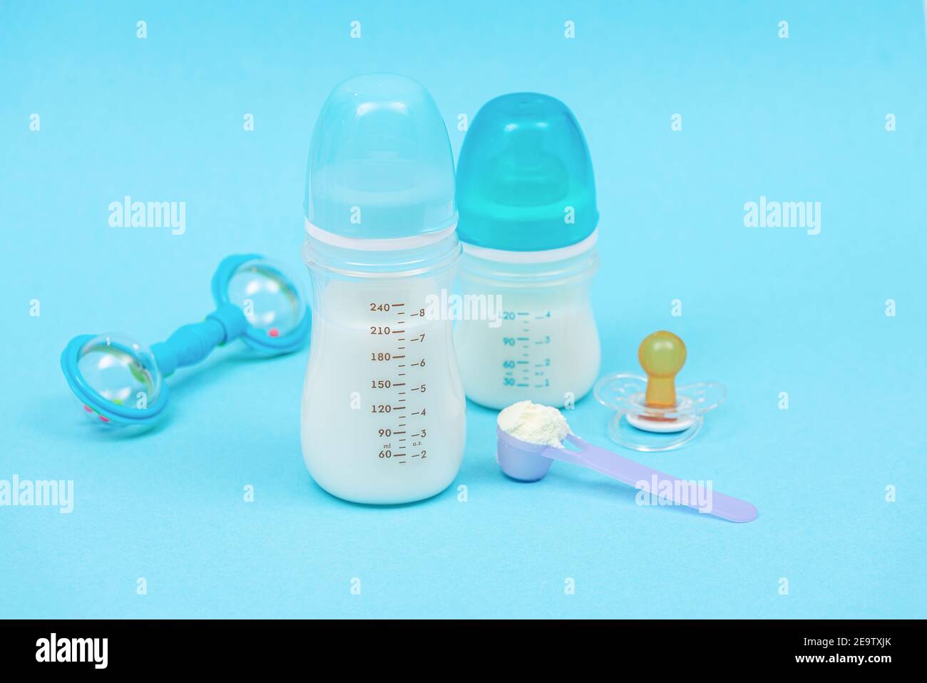 Préparation du mélange d'alimentation de bébé avec lait en poudre pour nourrissons en bouteille avec jouets. Arrière-plan bleu Banque D'Images