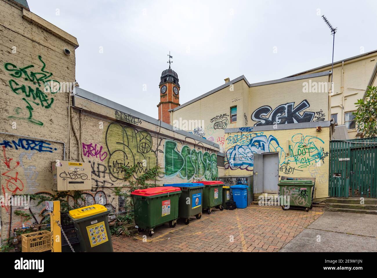 Avec l'horloge du bureau de poste de Newtown (Sydney) classée au patrimoine 1891 tour en arrière-plan les murs de cette voie arrière les zones sont couvertes de graffiti Banque D'Images