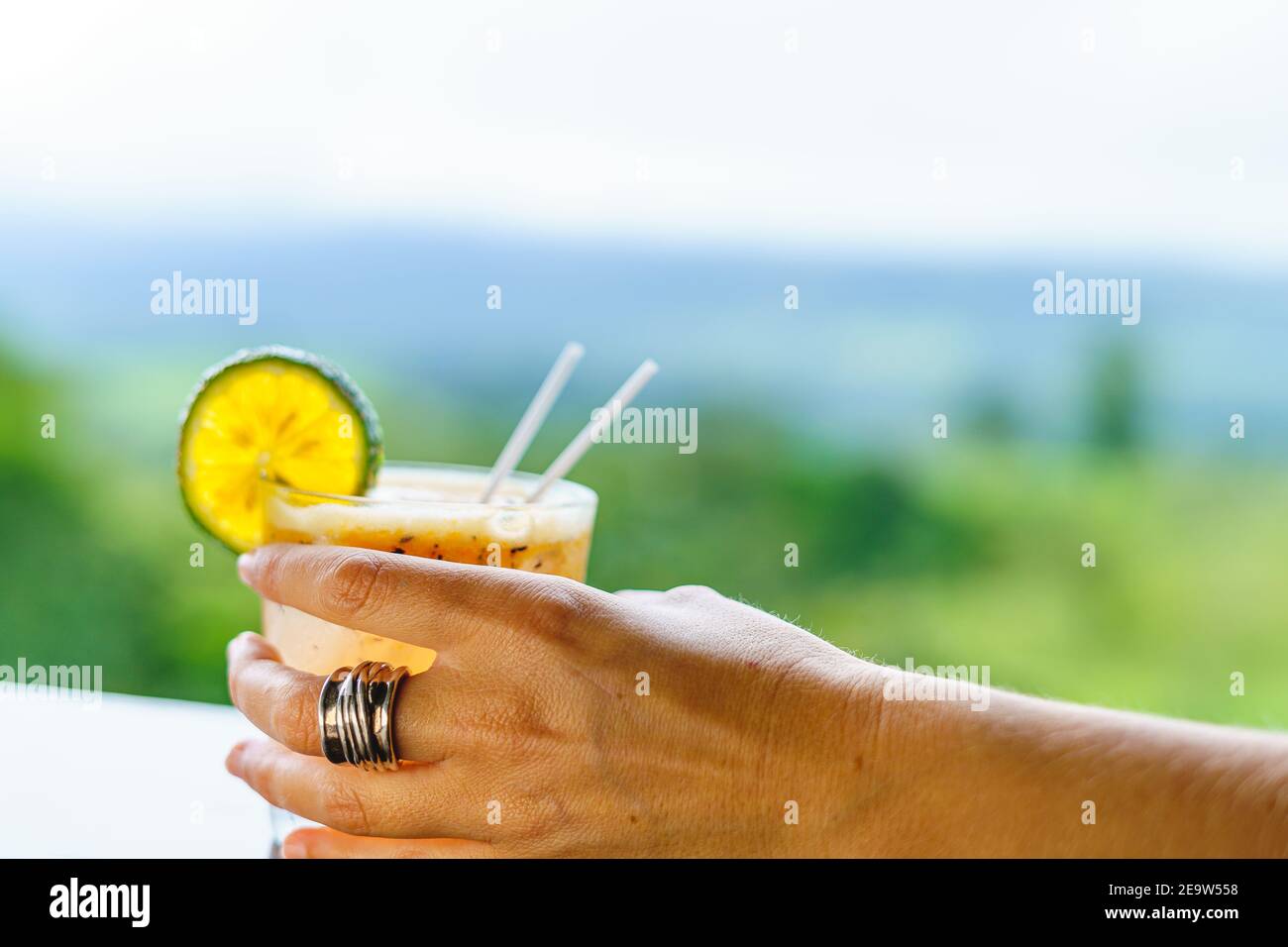 Main tenant un verre de michelada avec de la glace et du citron avec la jungle dans l'arrière-plan hors foyer. Costa Rica Banque D'Images