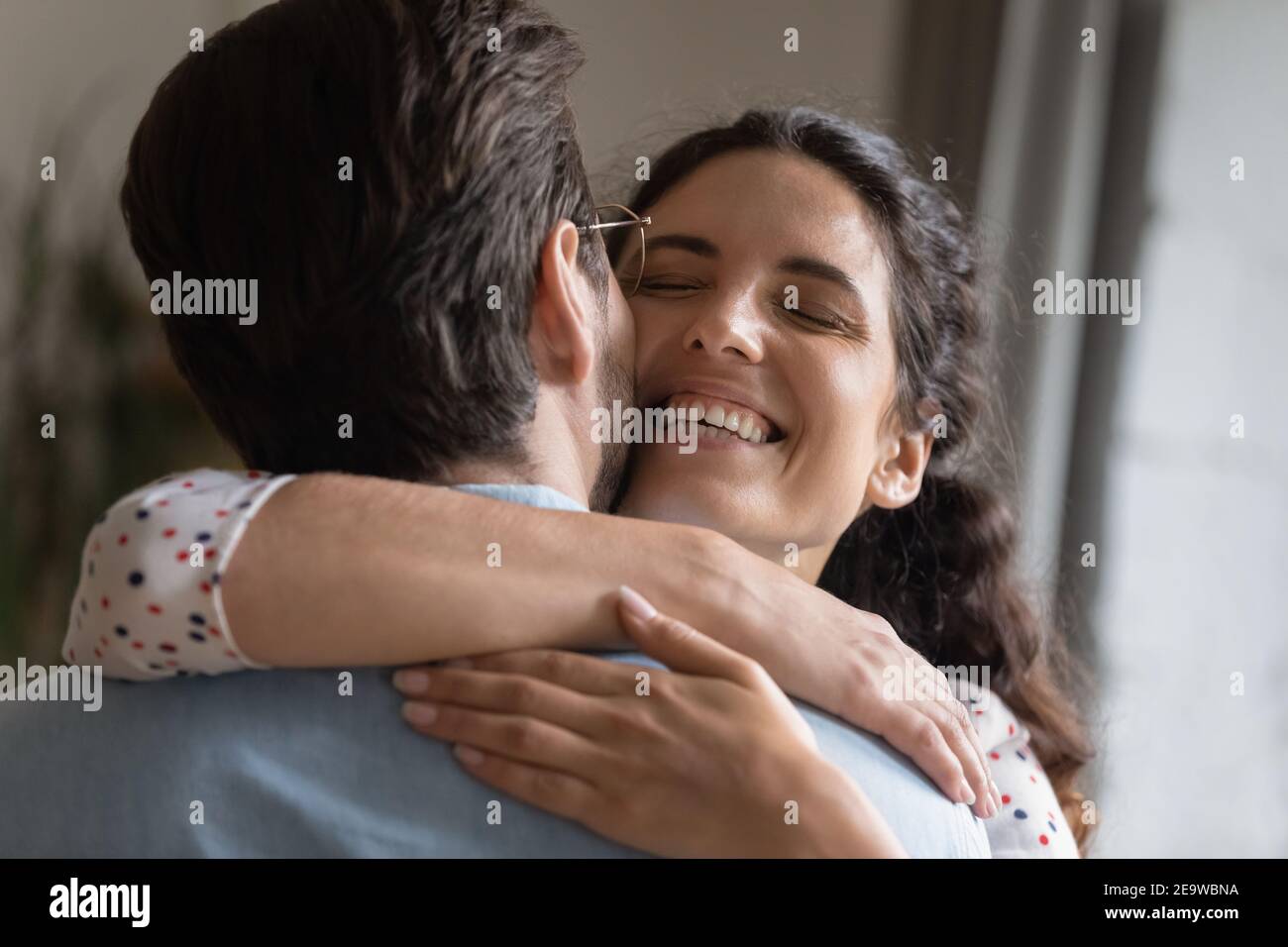 Femme du millénaire excitée embrassant la réunion de mari bien-aimé à la maison Banque D'Images