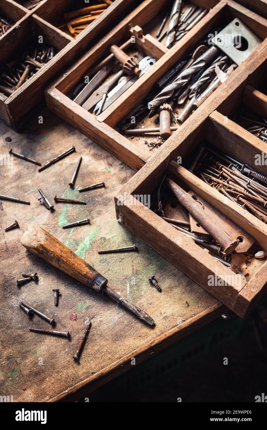 Tournevis et boulons avec boîte à outils sur table en bois. Outil de travail désordonné dans l'atelier de menuiserie. Équipement industriel d'époque Banque D'Images