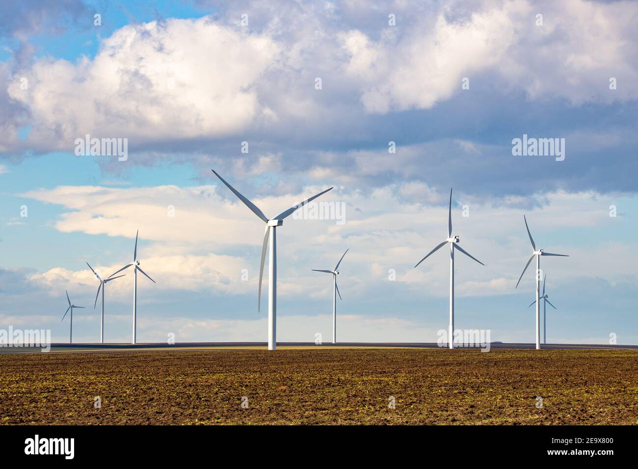 Beau paysage lumineux avec un Windfarm par une journée ensoleillée avec un ciel plein de nuages et coloré premier plan avec herbe vert-jaunâtre Banque D'Images