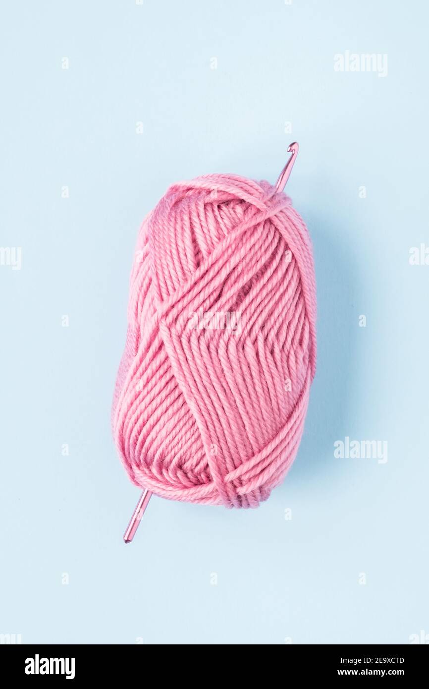 Crochet en crochet avec boules de fil rose sur un bleu arrière-plan Banque D'Images