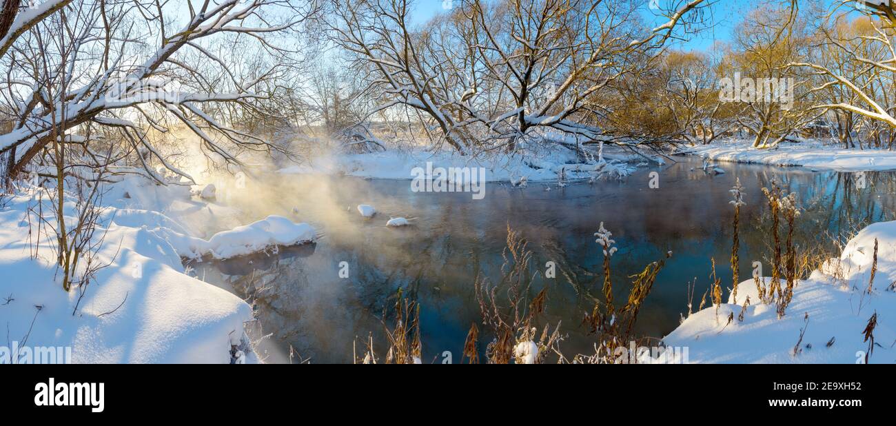 Paysage panoramique hivernal gelé avec rivière forestière pendant le matin ensoleillé de janvier. Banque D'Images