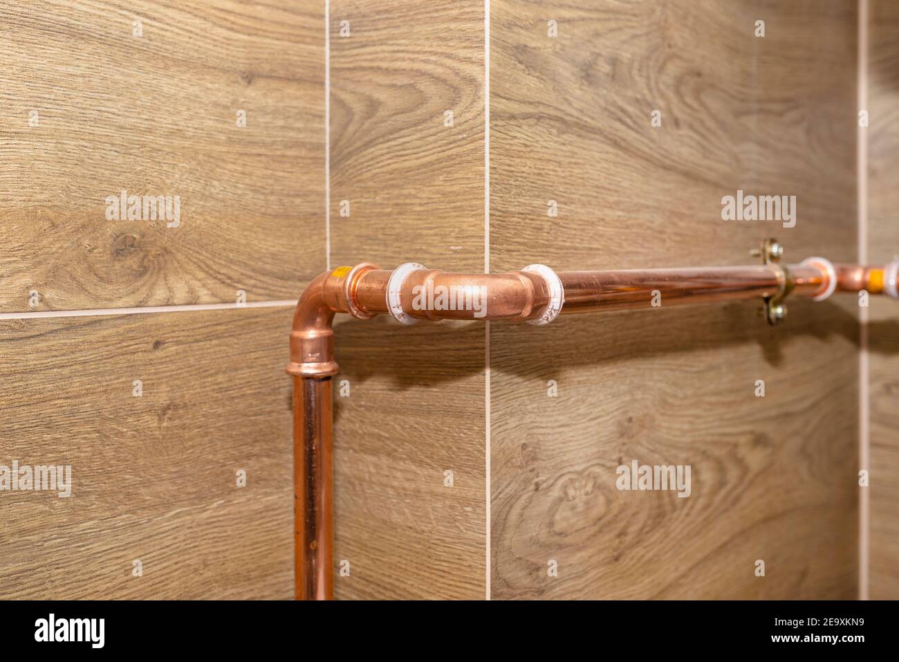 Tuyaux en cuivre pour installations au gaz naturel, fixés à un mur dans une chaufferie bordée de carreaux de céramique. Banque D'Images