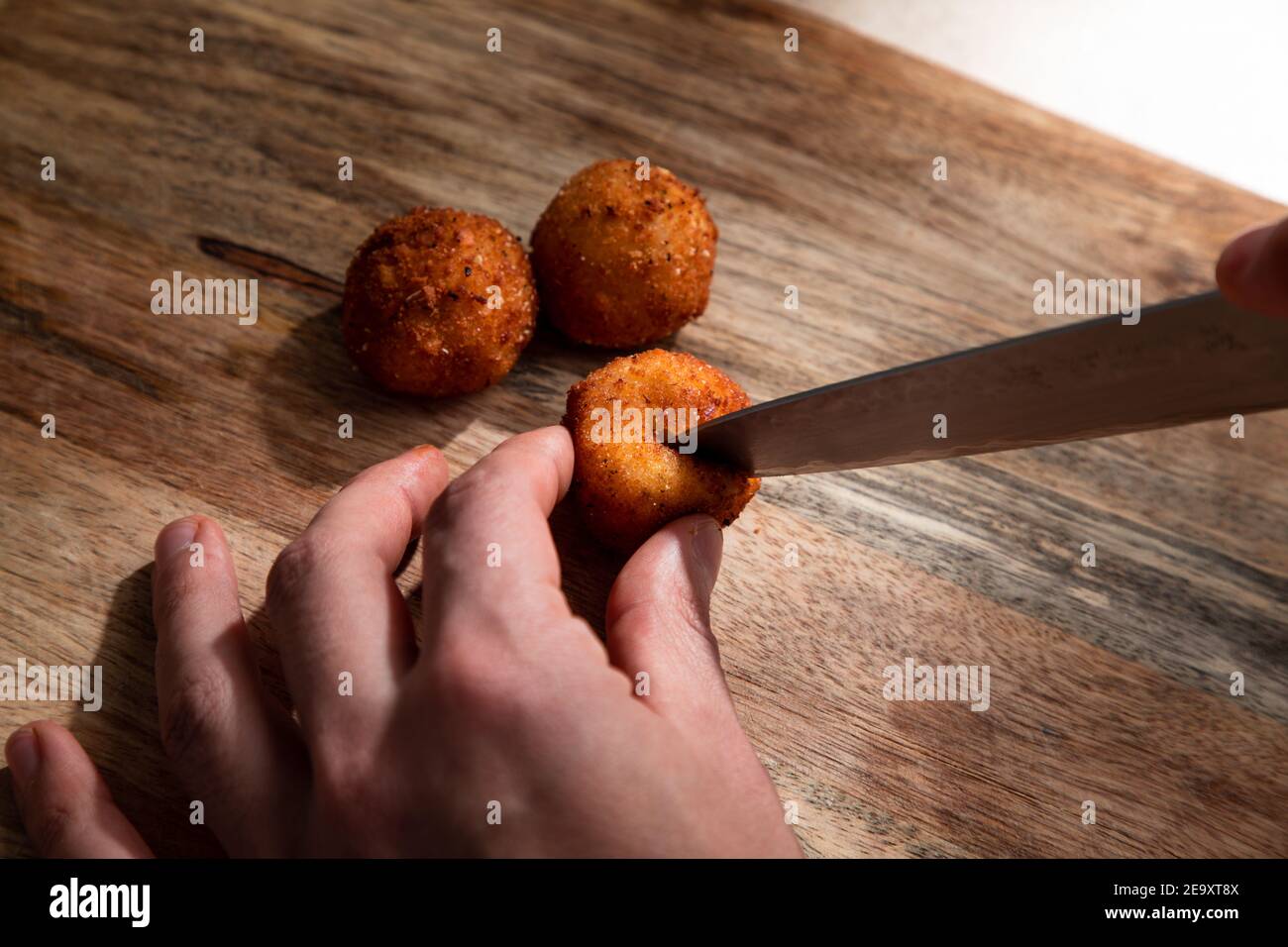 Du dessus de la récolte anonyme cuisinier couper croustillants frits profonds boule de fromage sur planche à découper en bois Banque D'Images