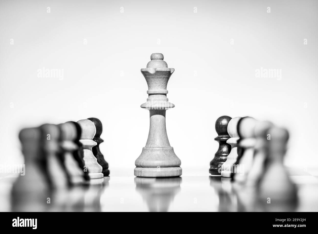 Chess White Queen sur chessboard, entouré de pions blancs et noirs dans un ton Low Key. (Copier l'espace) Banque D'Images