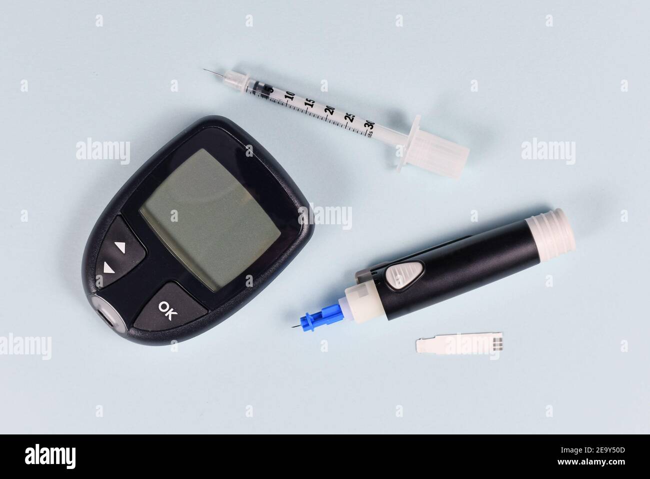 Équipement pour le traitement du diabète avec glucomètre, lancet, seringue et dispositif autopiqueur sur fond bleu Banque D'Images