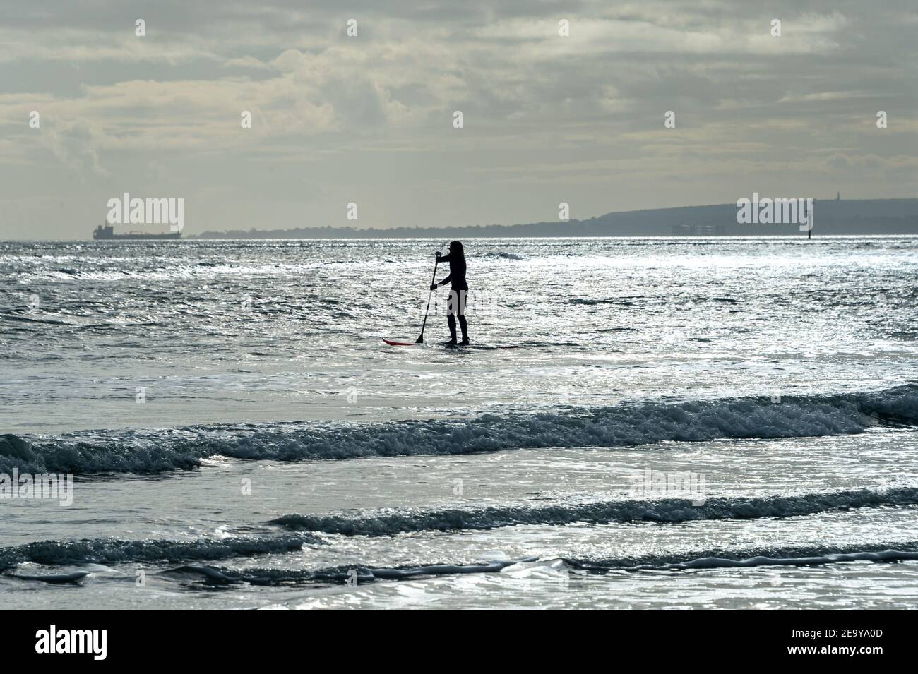 Paddleboarder solitaire avec lumière du soleil sur l'eau. Banque D'Images