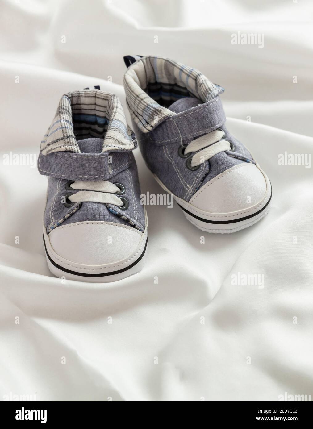 Baptême de baptême, baptême de bébé. Chaussons bébé garçon sur fond blanc  satiné. Chaussures douces pour bébé, nouveau-né, invitation, cérémonie,  chaussures en soie Photo Stock - Alamy