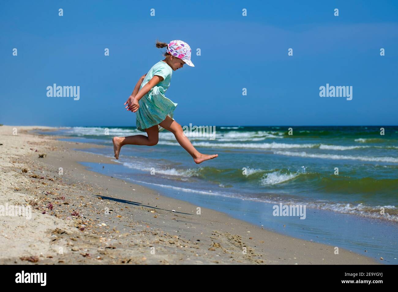 Petite fille sautant le long de la plage Banque D'Images