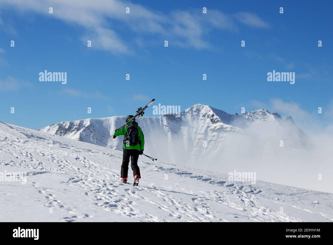 Skieur avec des skis sur son épaule monter au sommet de la montagne par temps froid. Hiver Caucase montagnes dans le brouillard, Géorgie, région de Gudauri. Banque D'Images