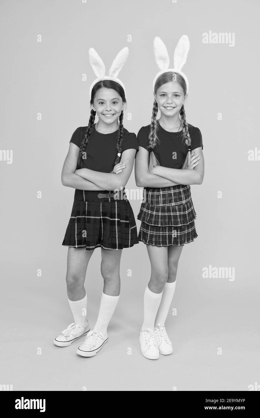 Uniforme scolaire pour petites écolières avec de longues oreilles de lapin. Jeux traditionnels de Pâques. Équipe de Bunny. Concept de divertissement et d'événement. Vacances de printemps. Enfants dans les oreilles de lapin de lapin. Famille et Sisterhood. Banque D'Images