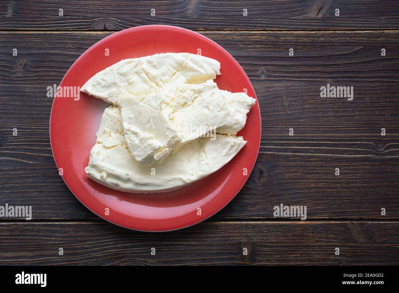 Cuisine des Balkans. Monténégro. Le fromage Pljevaljski est un fromage blanc doux local dans une assiette rouge sur une table rustique sombre. Copier l'espace Banque D'Images