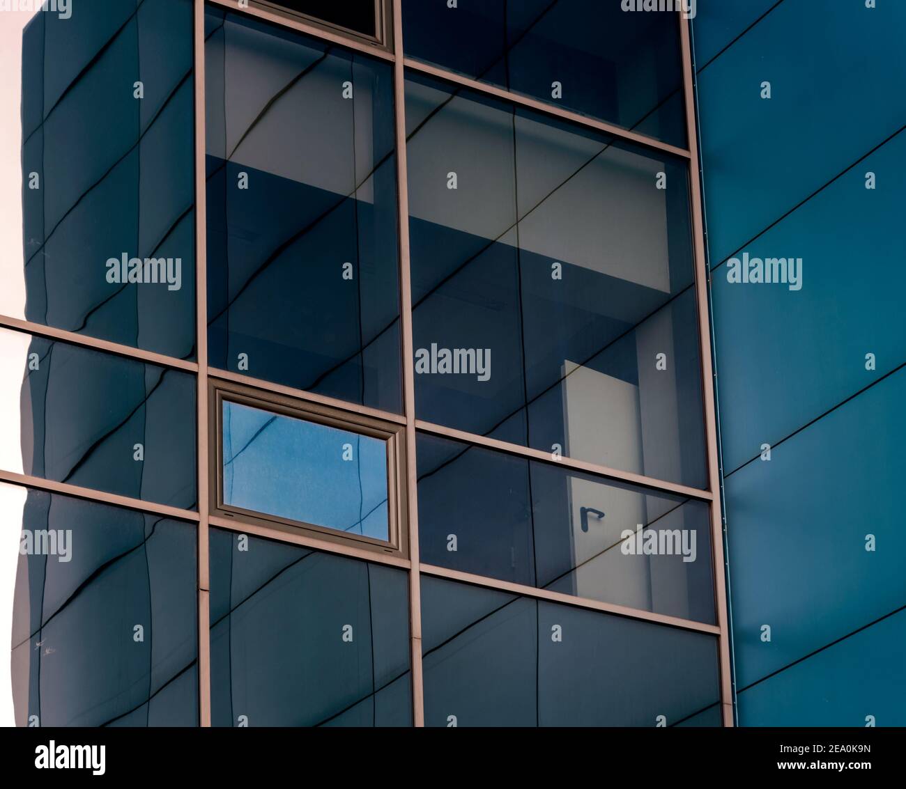 Fenêtres en miroir de la façade d'un immeuble de bureaux avec des panneaux bleu et jaune des châssis de fenêtre avec un reflet déformé de la chambre Banque D'Images