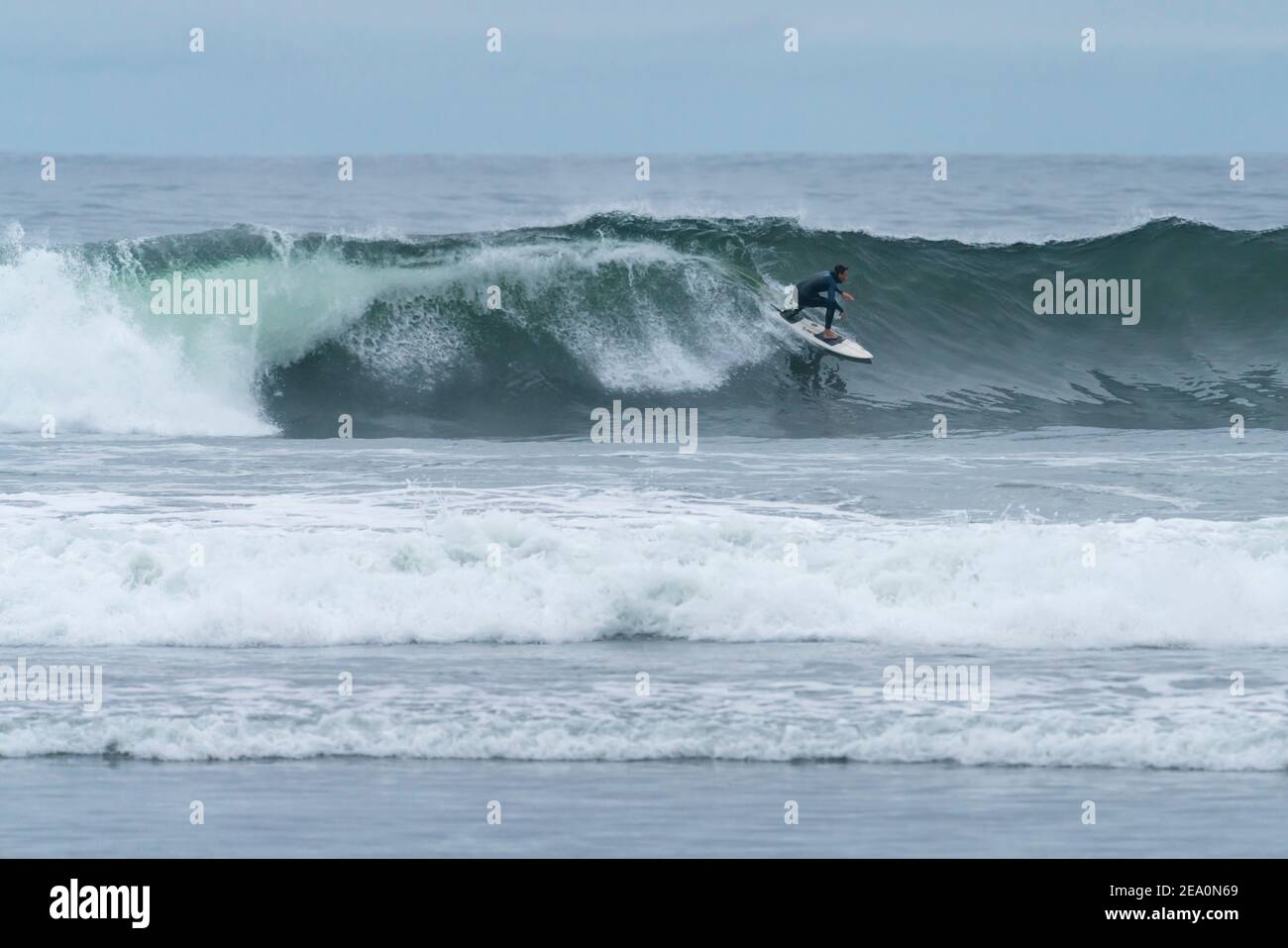 Un surfeur à cheval sur une grande vague dans l'océan Pacifique à la place Puertecillo au Chili. Des vagues incroyables pour surfer dans un paysage sauvage pendant une journée nuageux Banque D'Images