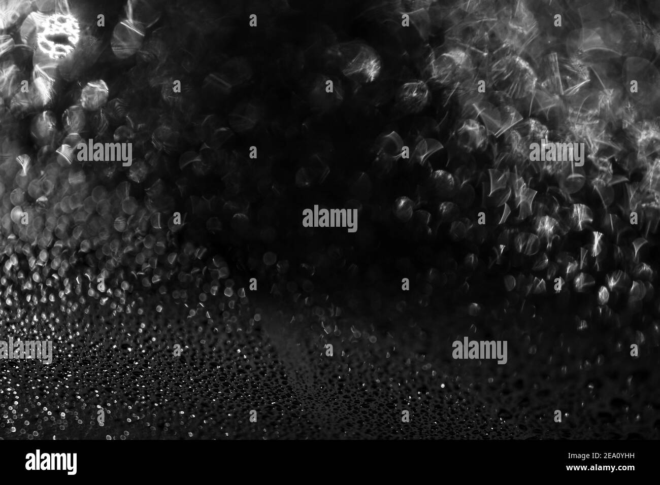 L'eau noire laisse tomber l'arrière-plan. De l'eau tombe sur un fond de verre de voiture. Gouttes d'eau sur fond noir bokeh en verre de voiture. Banque D'Images