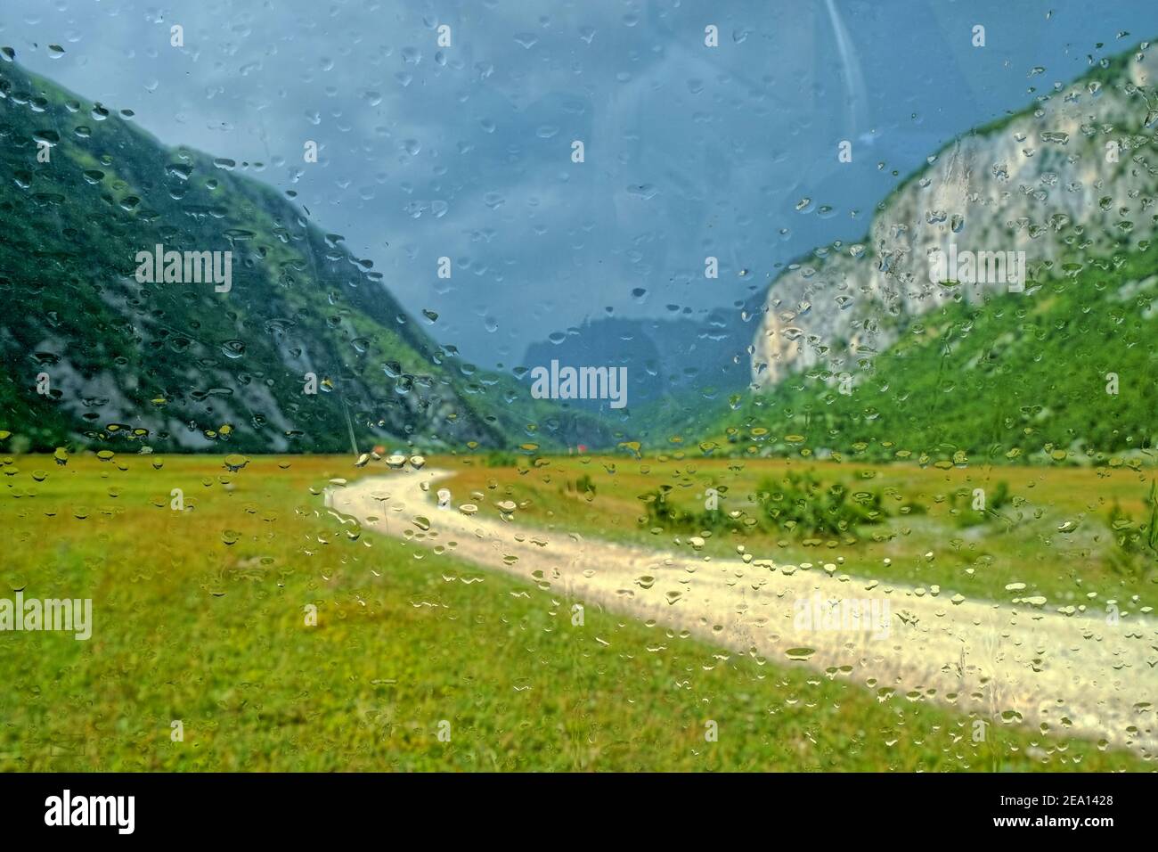 Gouttes de pluie sur un verre de voiture, au-delà d'une vue floue de la route de terre dans le canyon de Komarnica, au Monténégro Banque D'Images