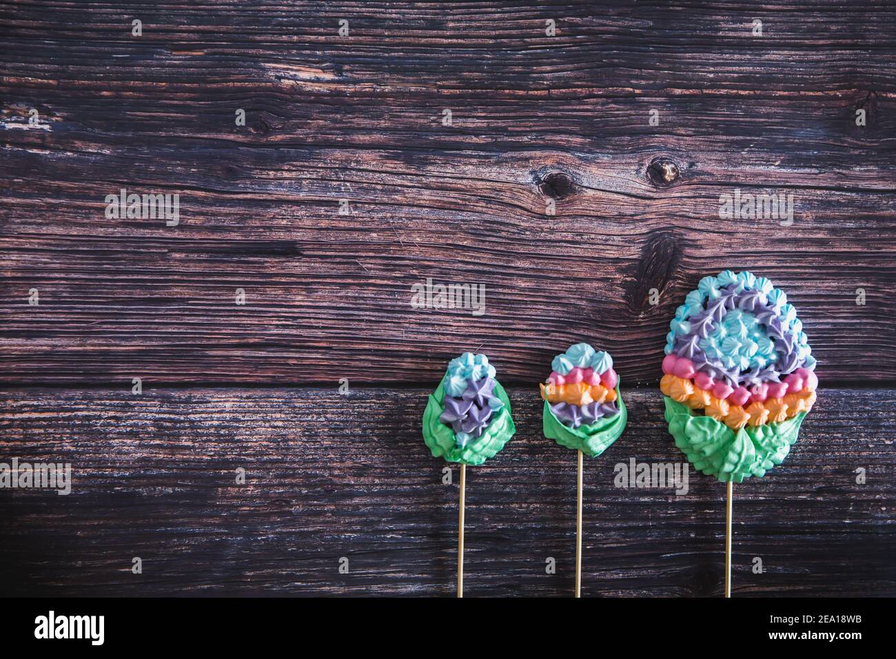 Meringues maison douces et colorées sous forme d'œufs sur fond de bois. Pose à plat. Vue de dessus. Beaucoup de zèphans doux. Image de dessert tendance avec vue sur le dessus. Banque D'Images