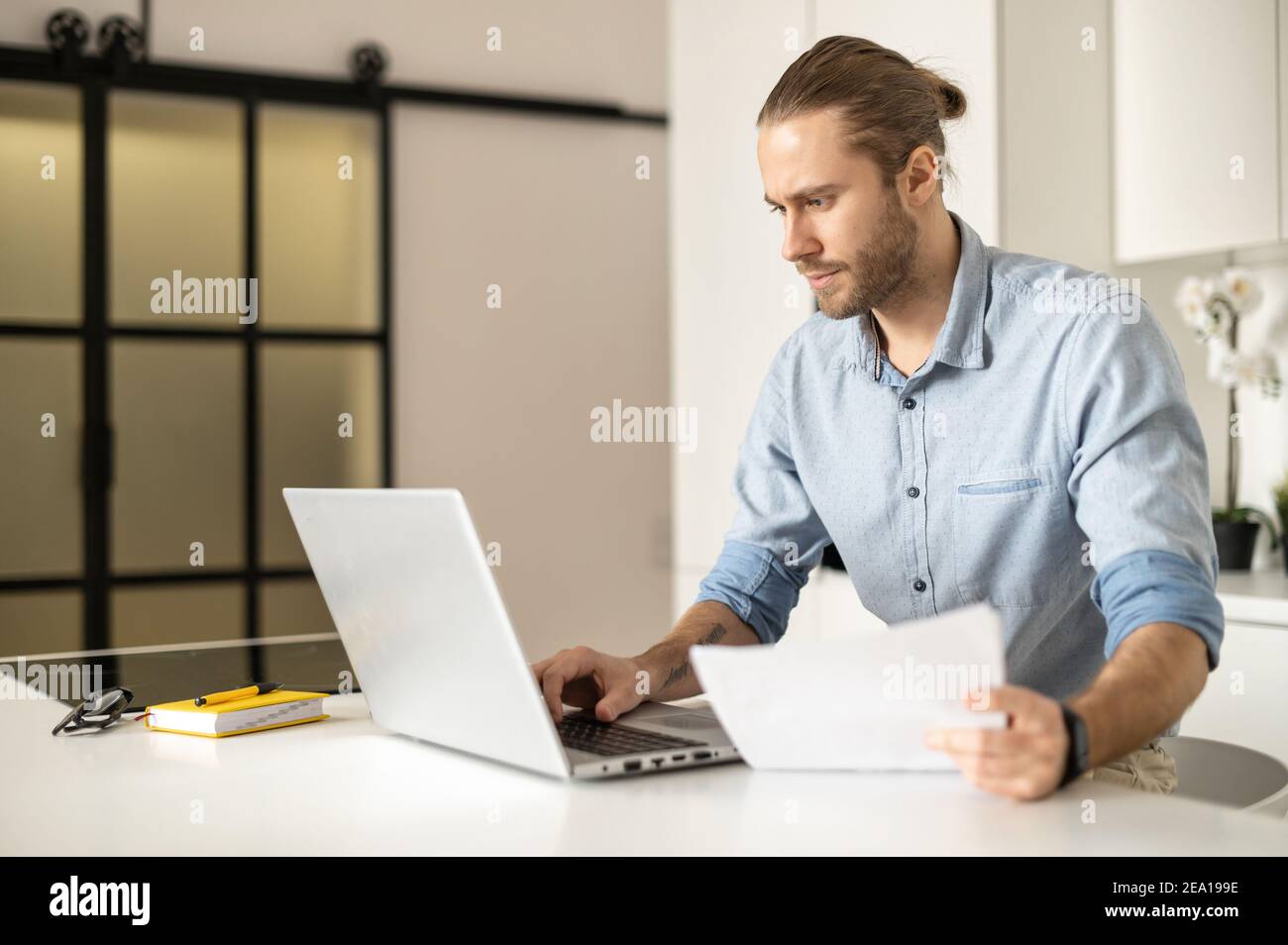 Un homme concentré avec un ordinateur portable travaille sur le projet à distance, un jeune entrepreneur regarde les documents de travail, analyse, contrôle des données. Un homme Banque D'Images