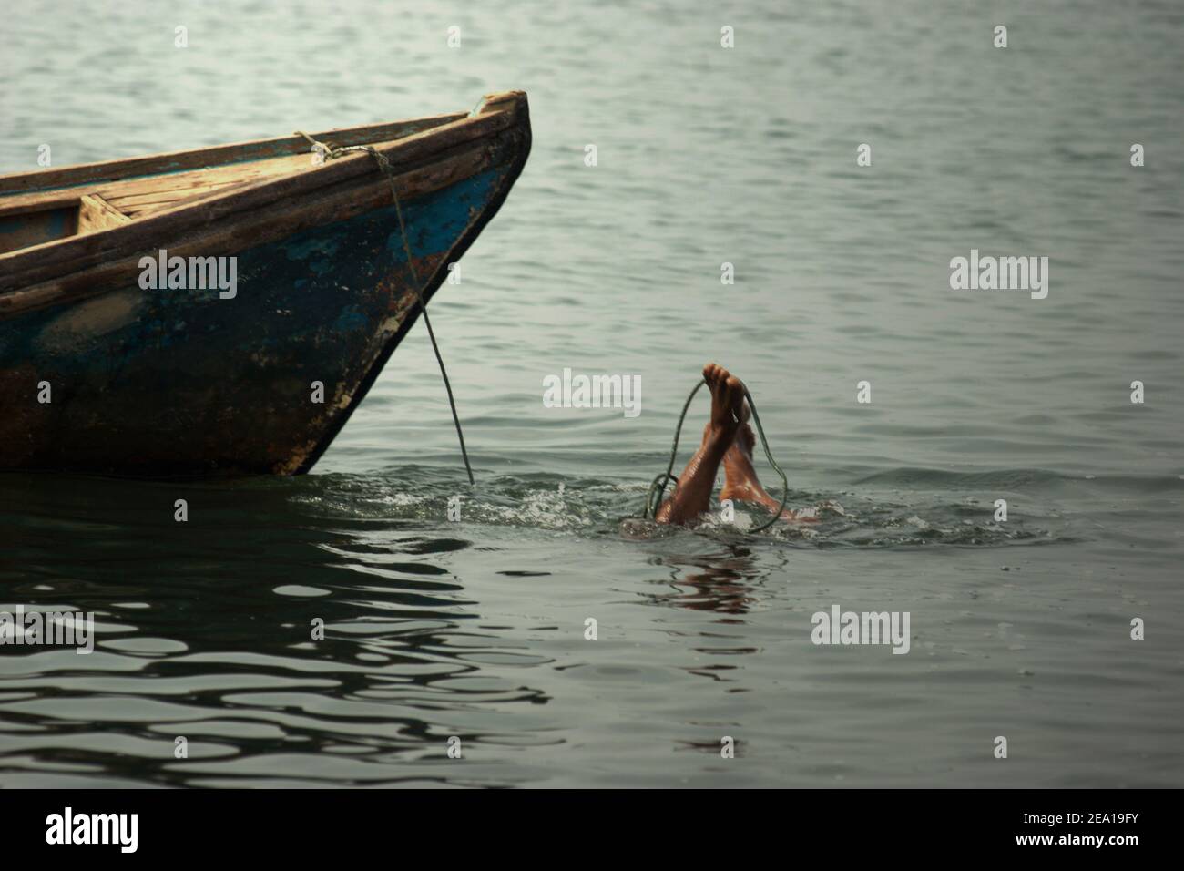 Un homme plonge pour rechercher des objets utiles ou précieux sur les eaux côtières de Jakarta dans la région de Muara Baru, Penjaringan, Nord de Jakarta, Jakarta, Indonésie. Banque D'Images