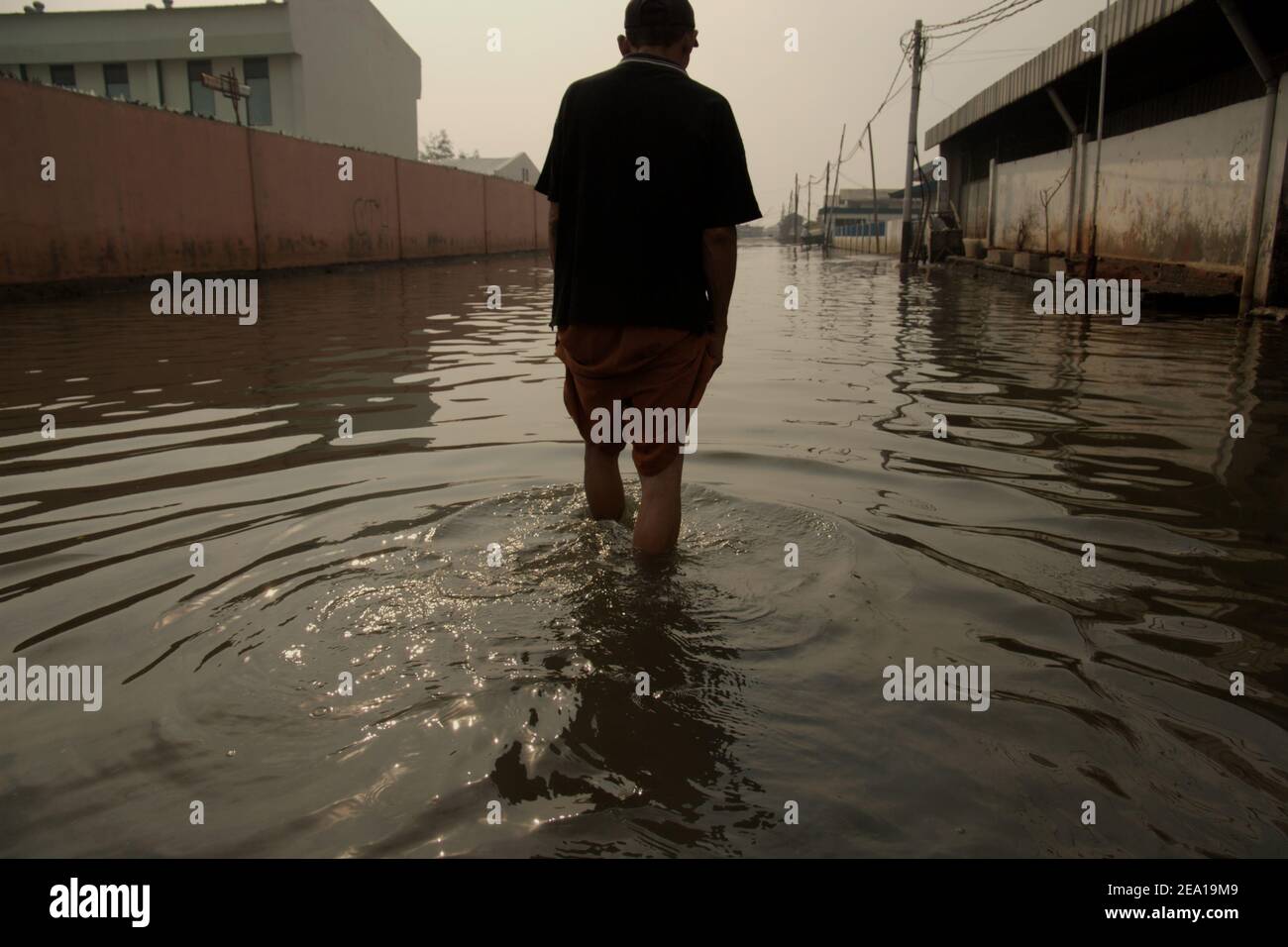 Un homme marchant dans une rue inondée d'eau de mer à Penjaringan, dans la zone côtière de Jakarta, en Indonésie. Banque D'Images