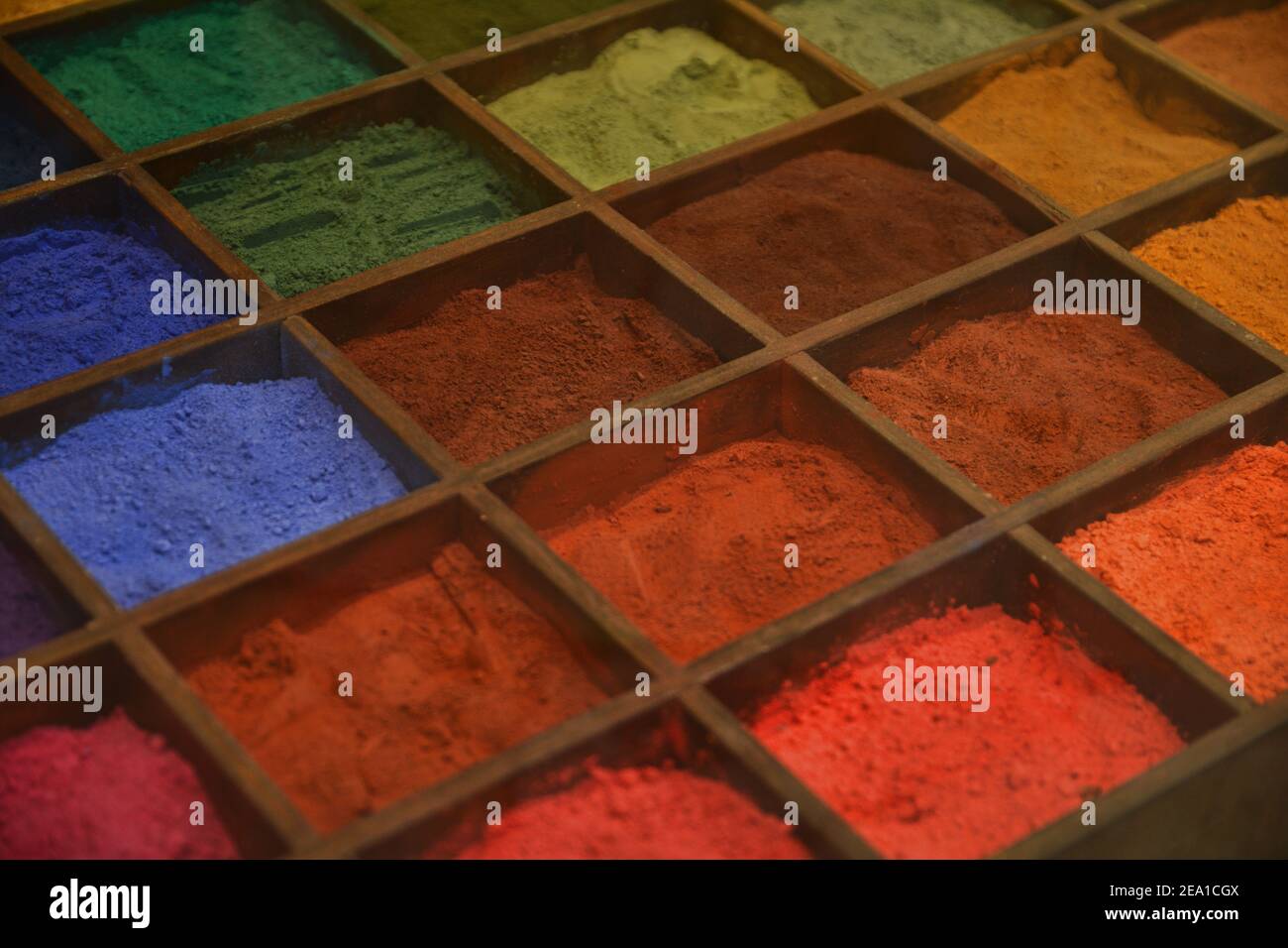 Poudres de couleurs artistiques dans une boîte en bois avec compartiments. Arrière-plan texturé coloré. Banque D'Images