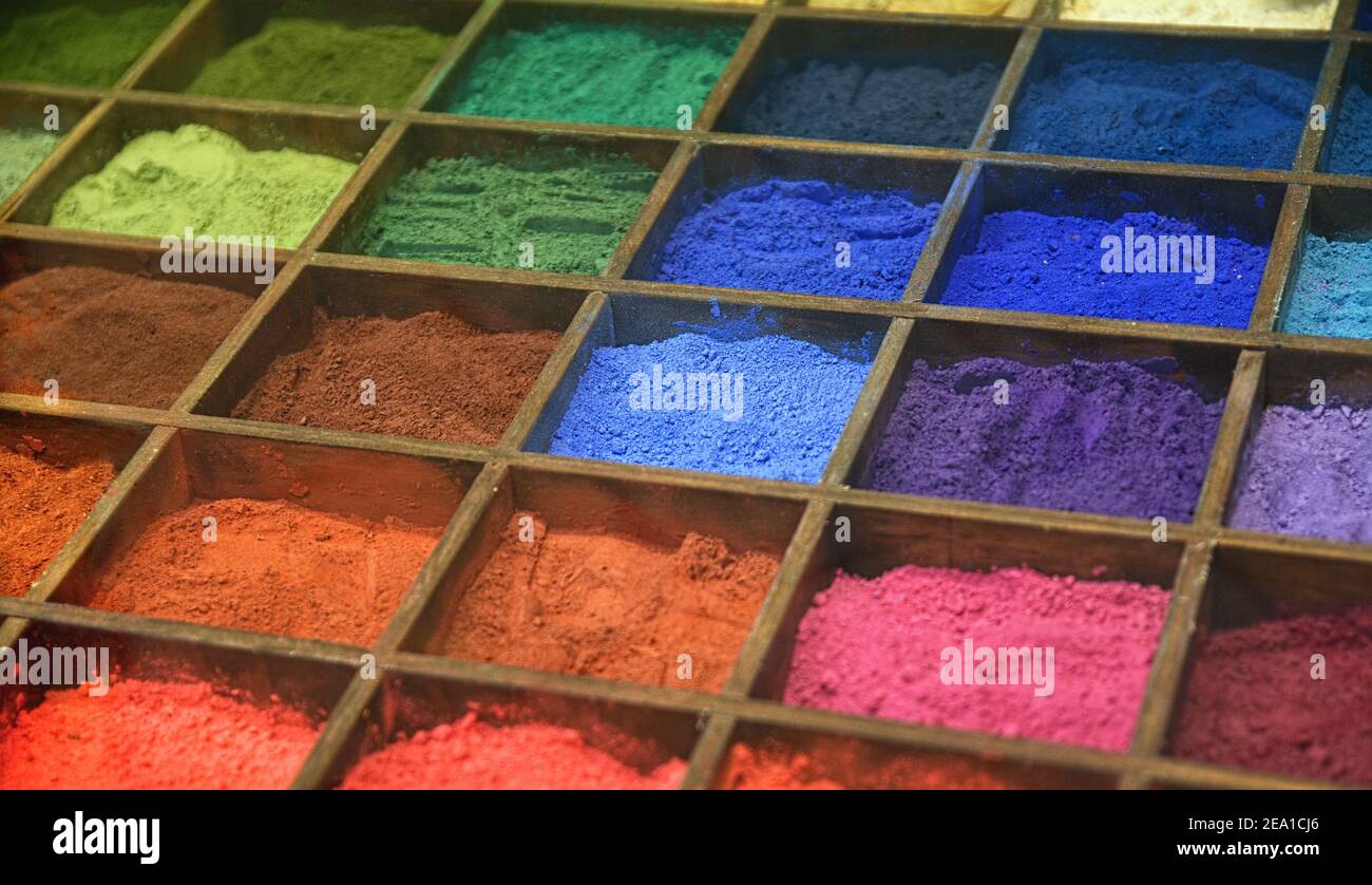 Poudres de couleurs artistiques dans une boîte en bois avec compartiments. Arrière-plan texturé coloré. Banque D'Images